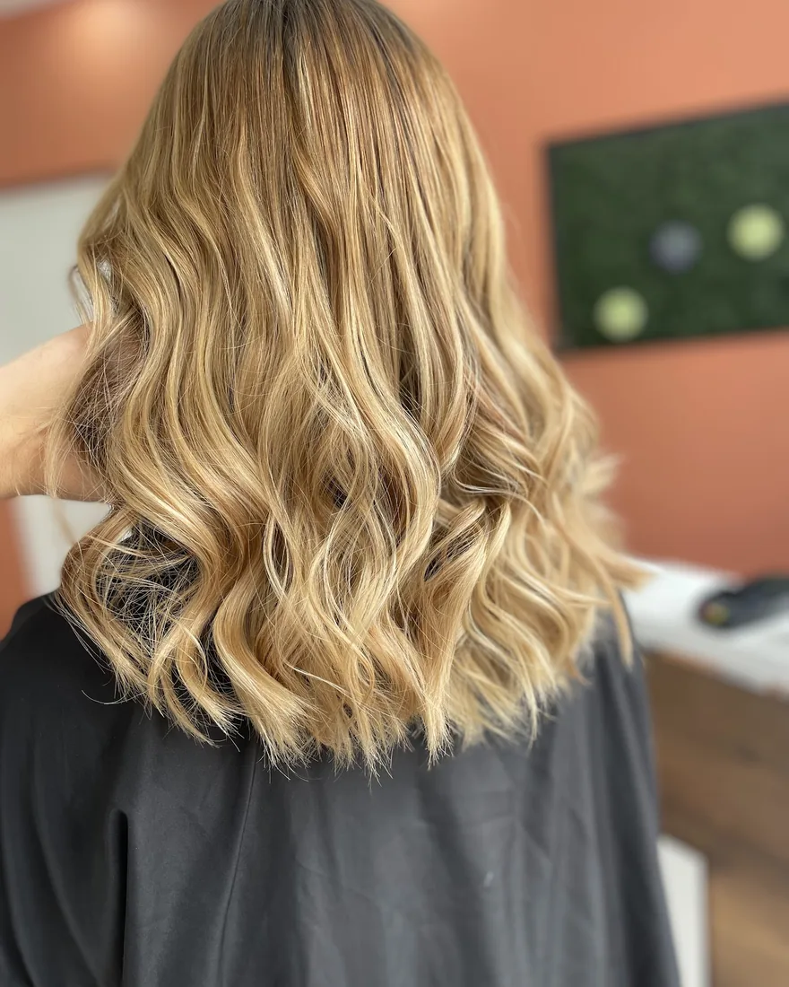 Balayage blond ondulé réalisé chez Machin Coiffure, coiffeur à Calais