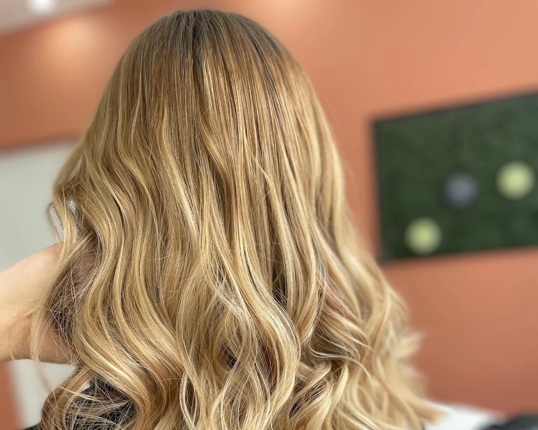 Cheveux longs ondulés blonds coiffés chez Machin Coiffure à Calais
